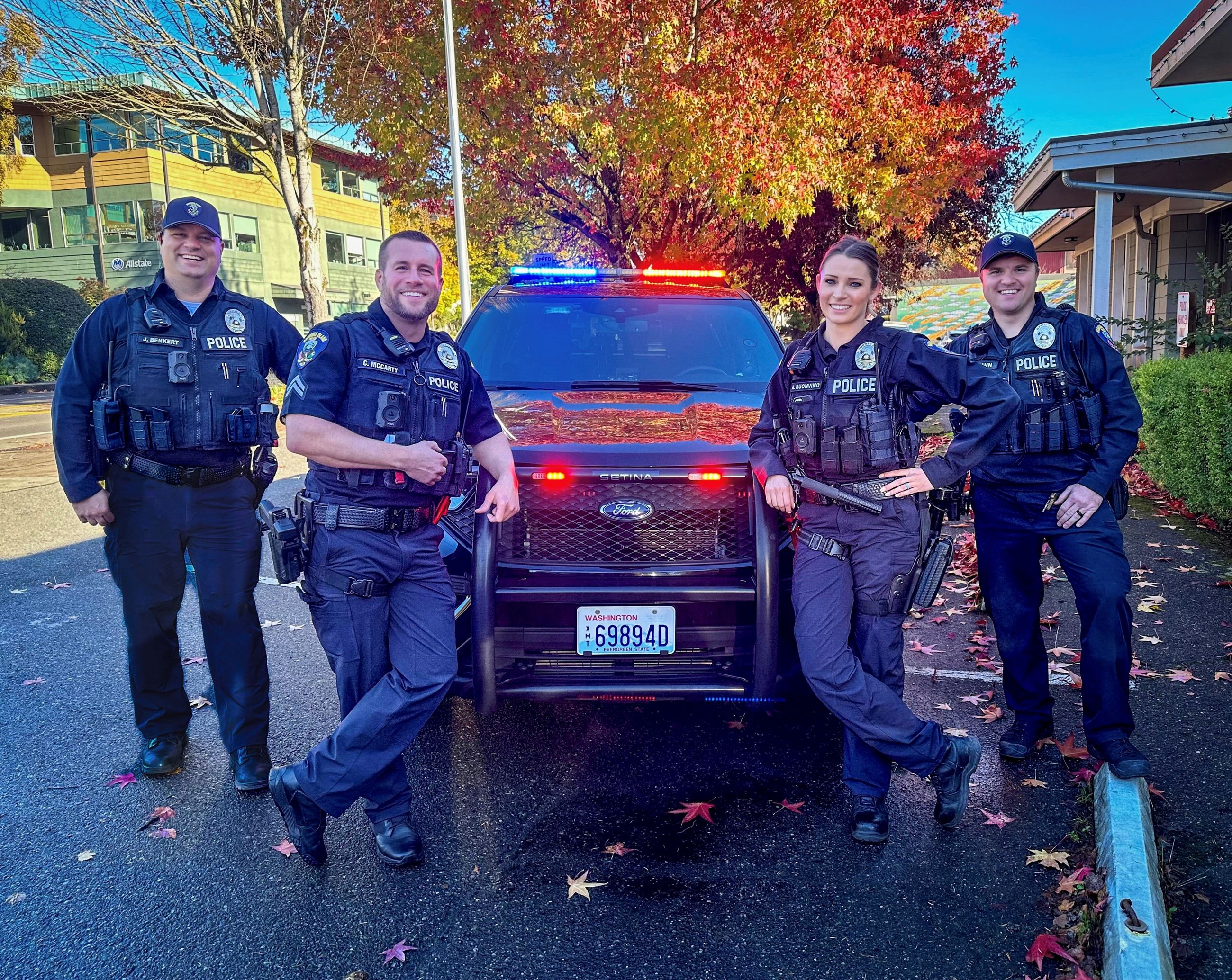 Photo of police officers Smiling in front of squad car.